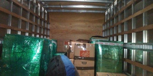 Interior of a moving truck, partially filled with wrapped furniture and boxes.