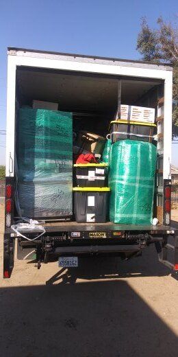 Back of a truck loaded with boxes and wrapped items, ready for a move.