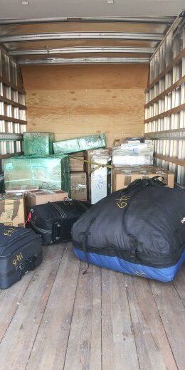 Inside of a truck with various items including wrapped boxes and large bags.