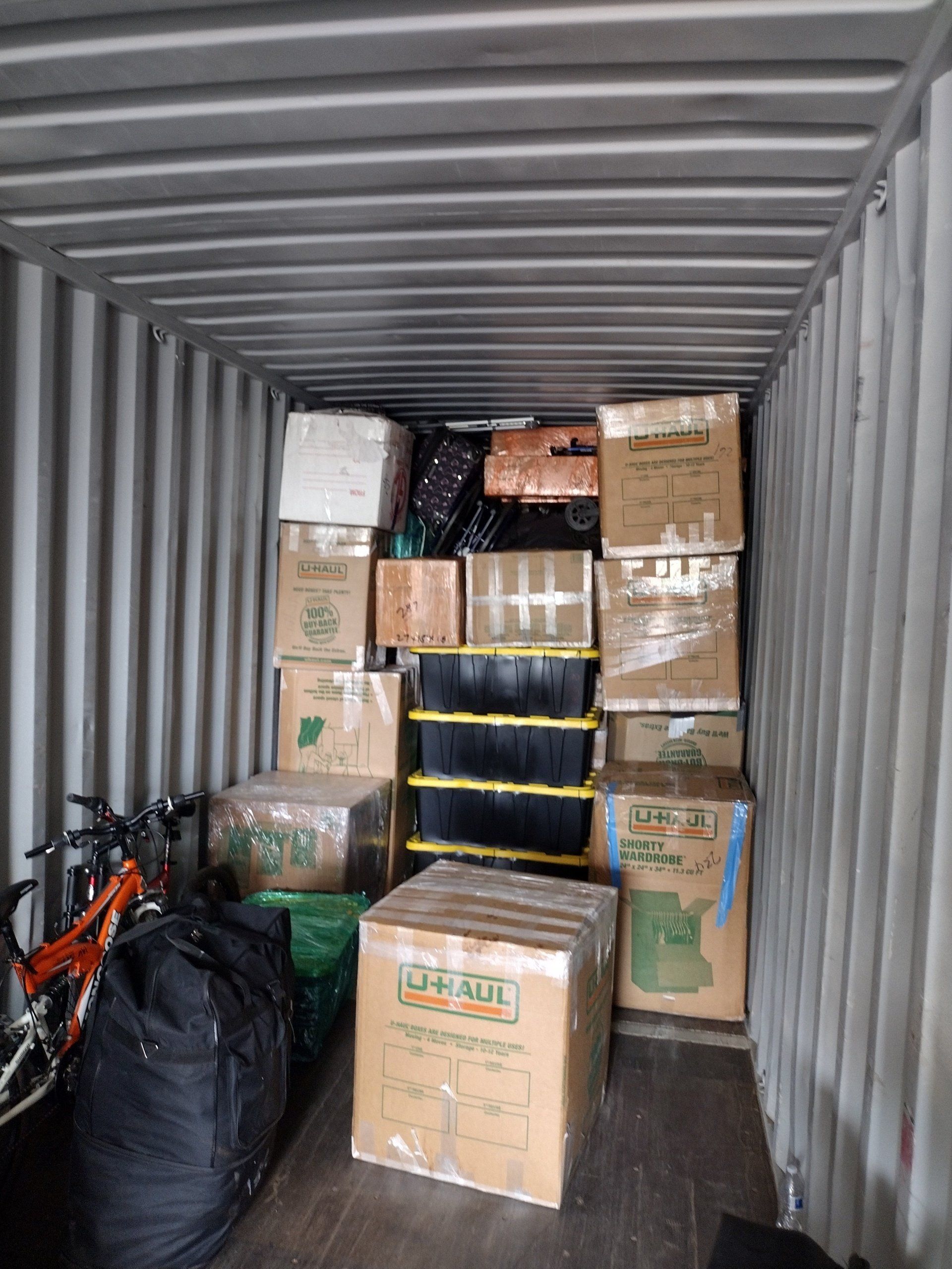 Boxes and items packed inside a storage container; bicycles are on the left.