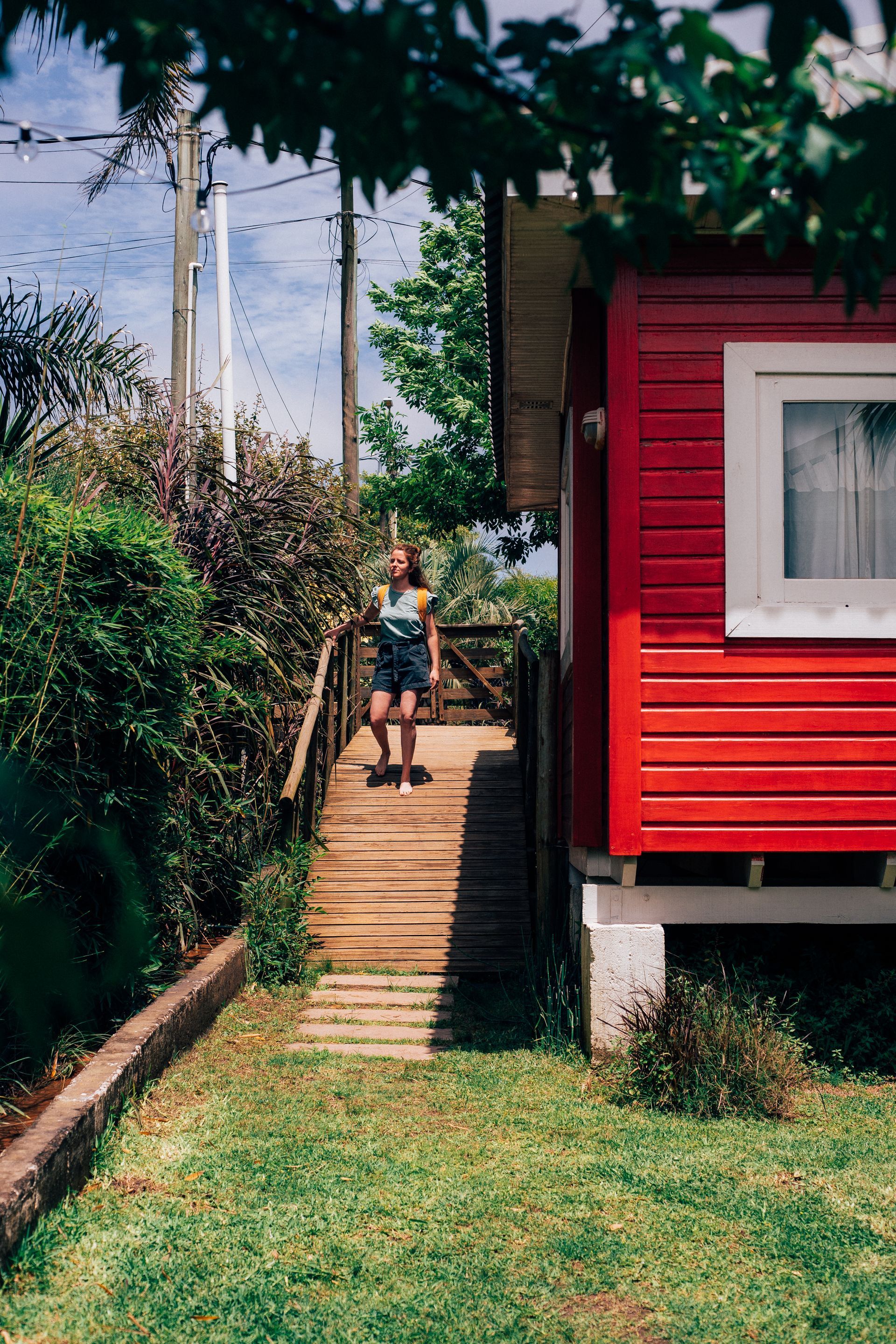 A woman is standing on a wooden ramp leading to a red house.