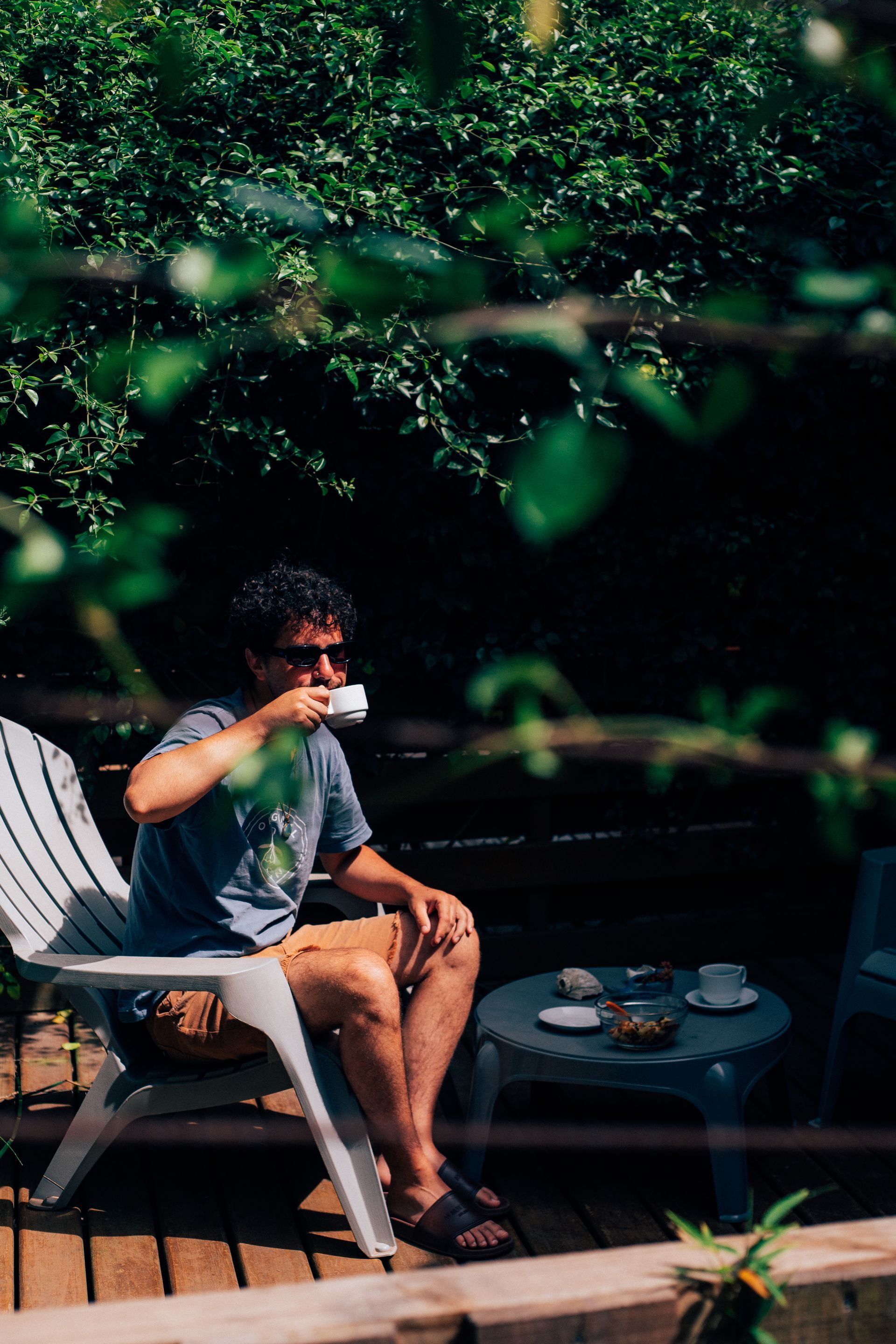 A man is sitting in a chair drinking a cup of coffee.