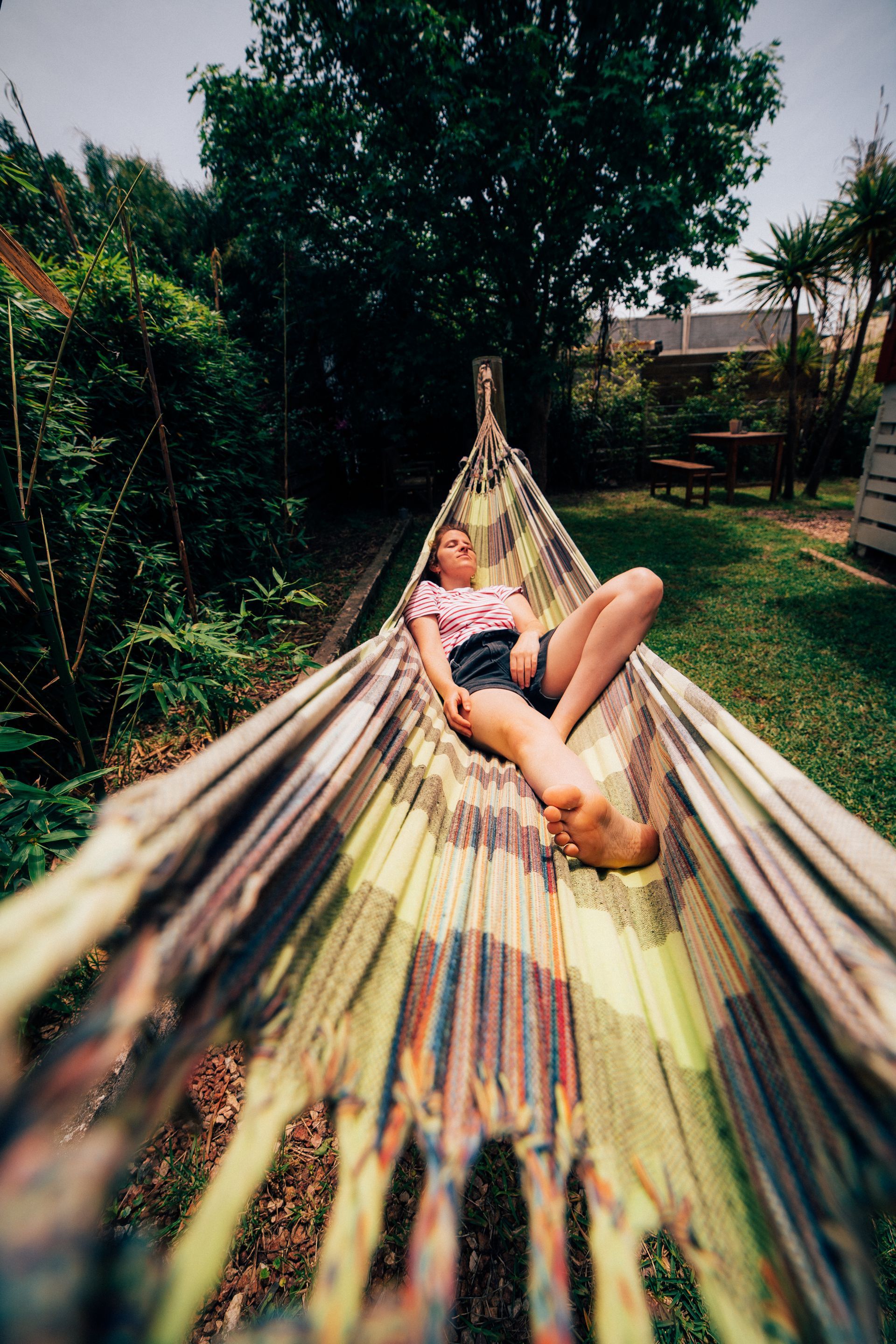 A woman is laying in a hammock in a garden.