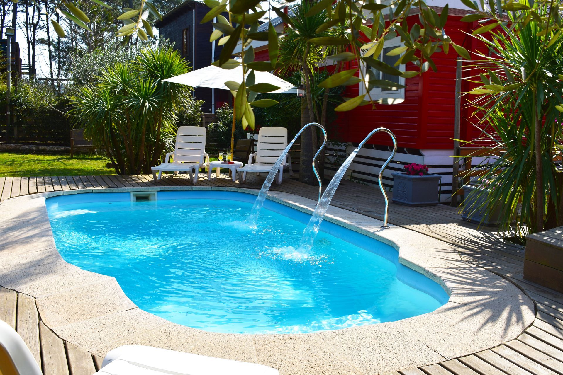 A swimming pool with a red house in the background