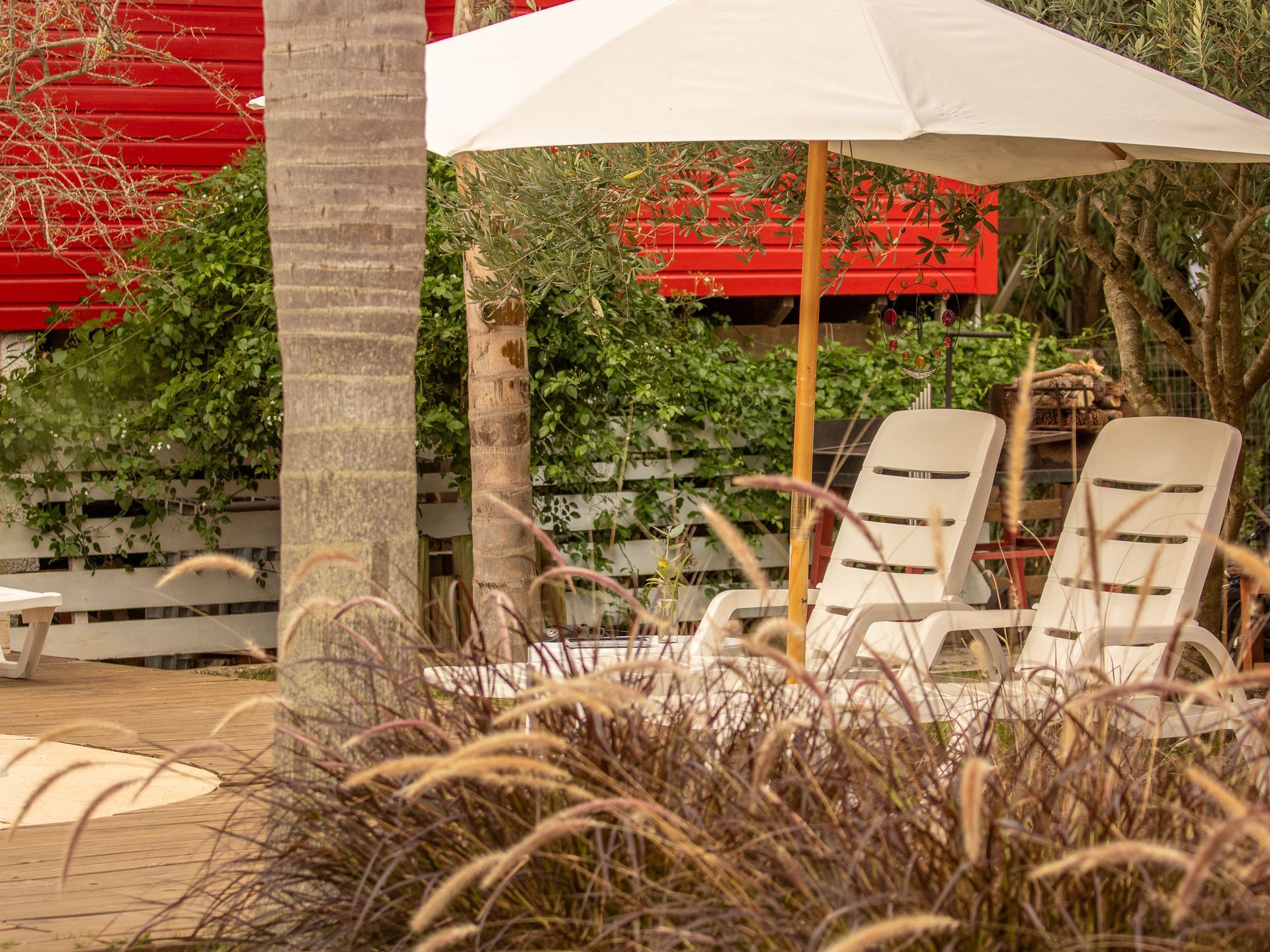 A couple of chairs under an umbrella in front of a red building.