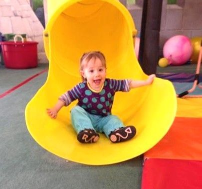 A baby girl is crawling on the floor and smiling.