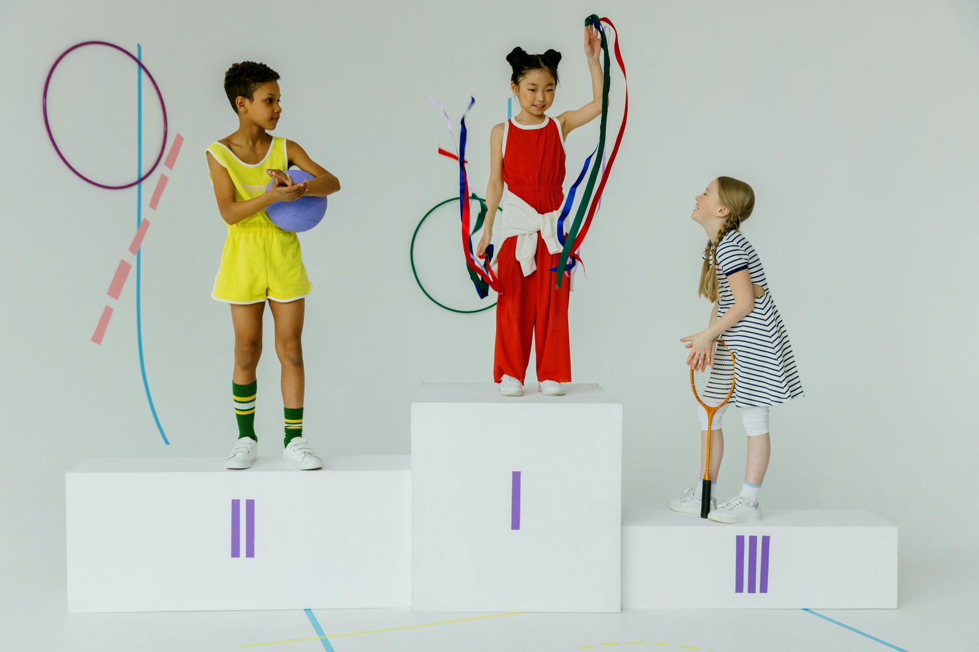 Three young girls are standing on a podium holding ribbons.