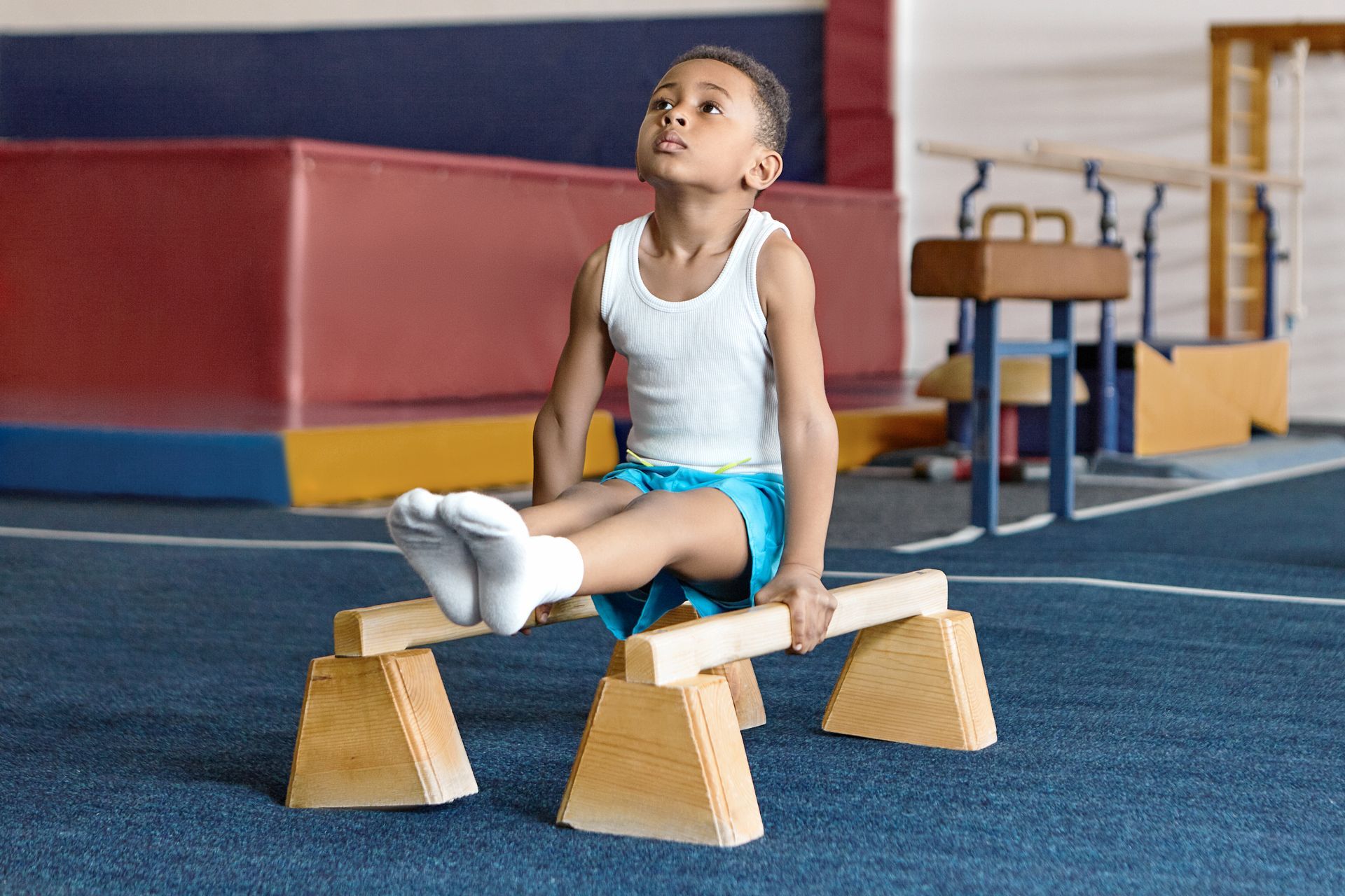 A little girl is doing a split on a blue mat