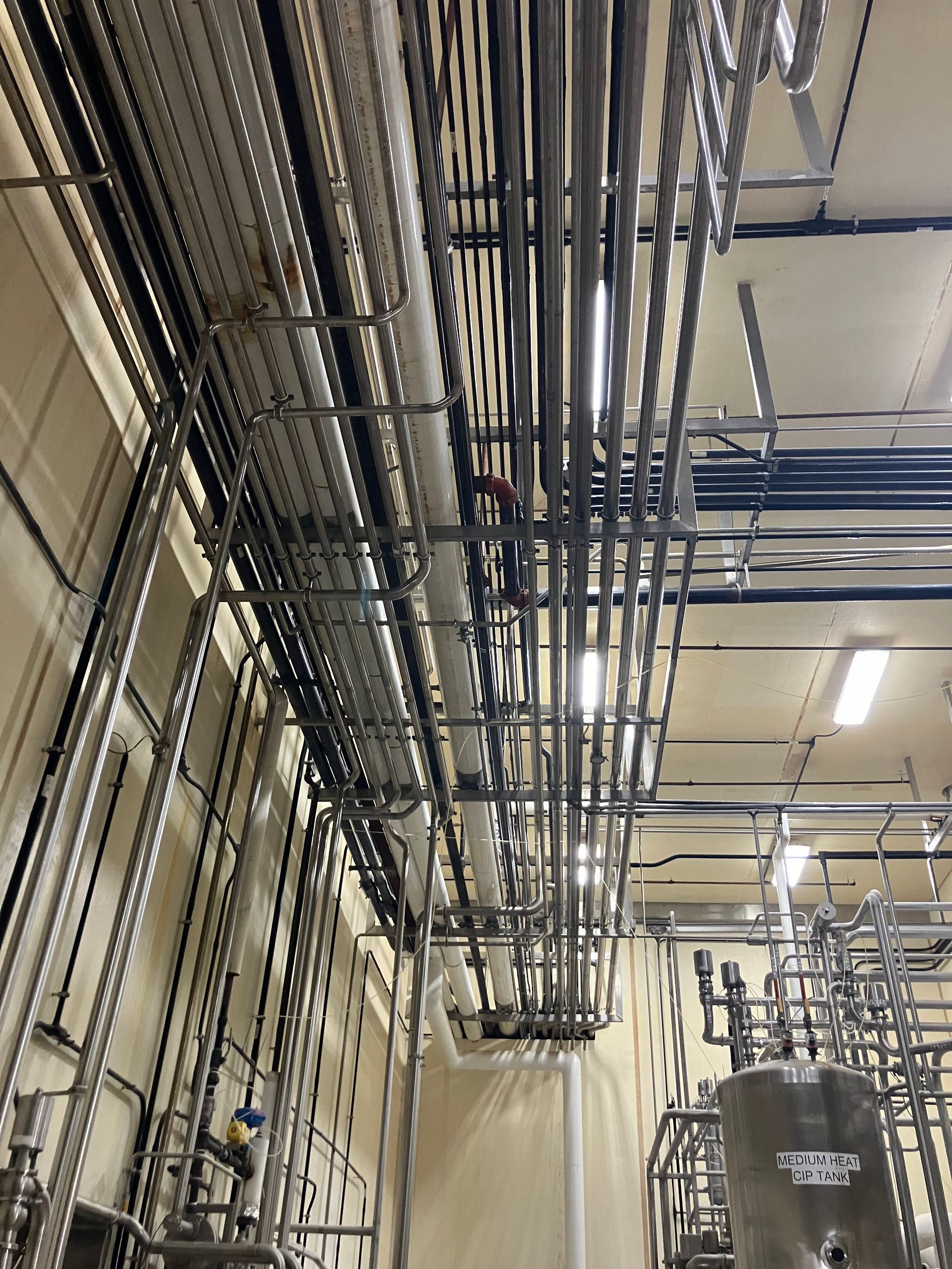 Industrial room with many stainless steel pipes running across the ceiling and walls.