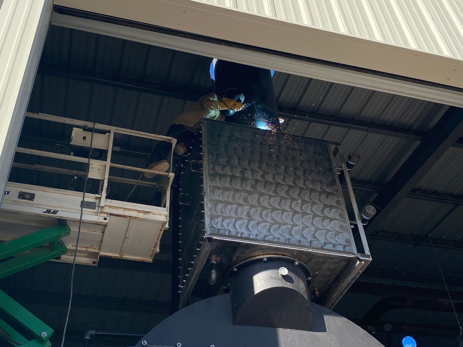 Welder on a lift welding metal structure to building's ceiling.