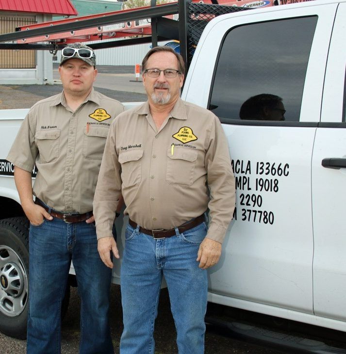 Two men in work uniforms standing next to a white truck, possibly for a service company.