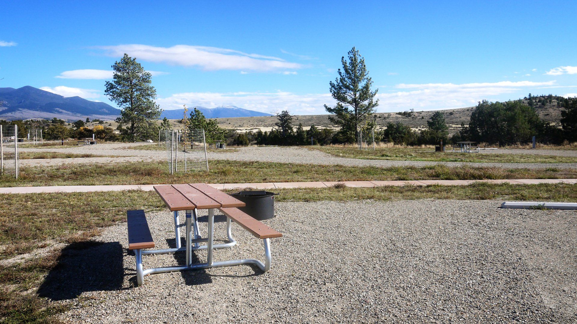 A picnic table in a gravel area with mountains in the background