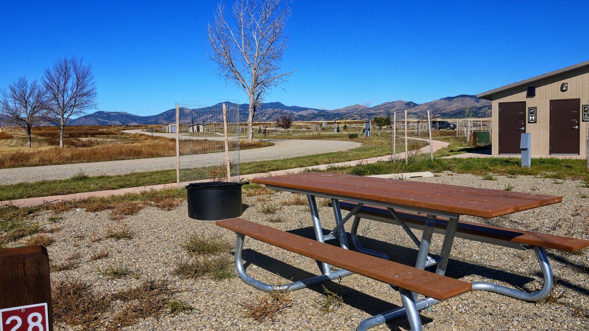 A picnic table is sitting in the dirt in front of a building.