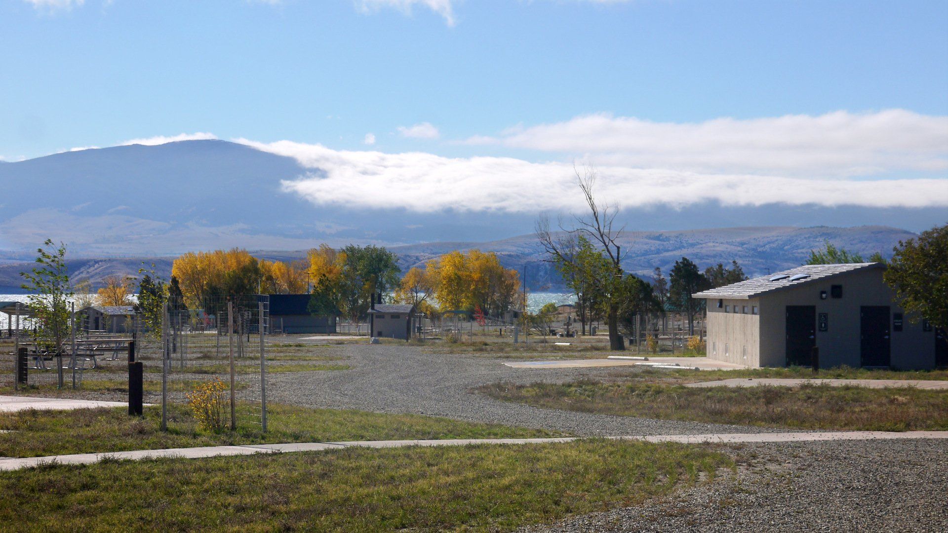 A row of buildings in a field with mountains in the background.