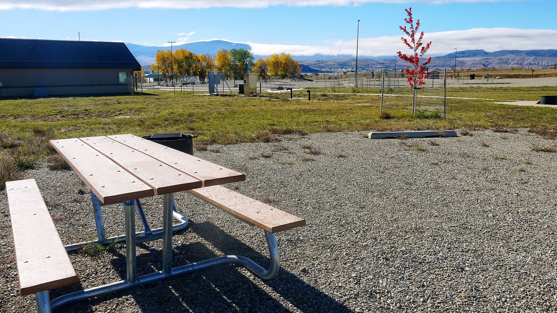A picnic table is sitting in the middle of a gravel field.
