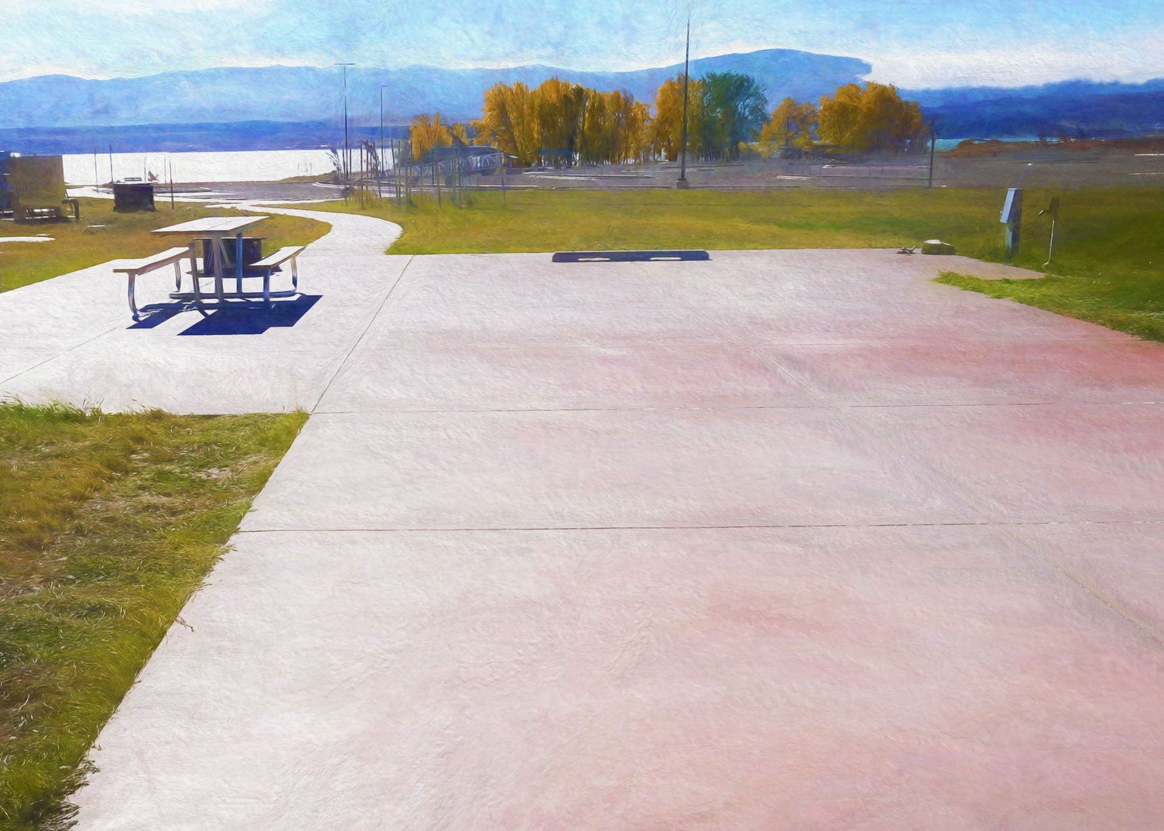 A concrete walkway with a picnic table in the background