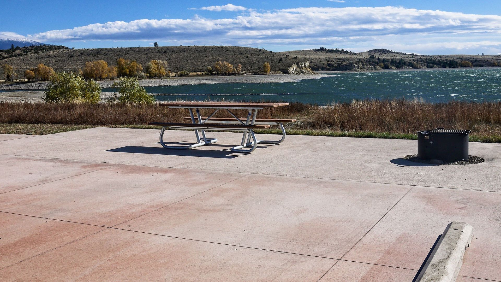 A picnic table is sitting in front of a lake.