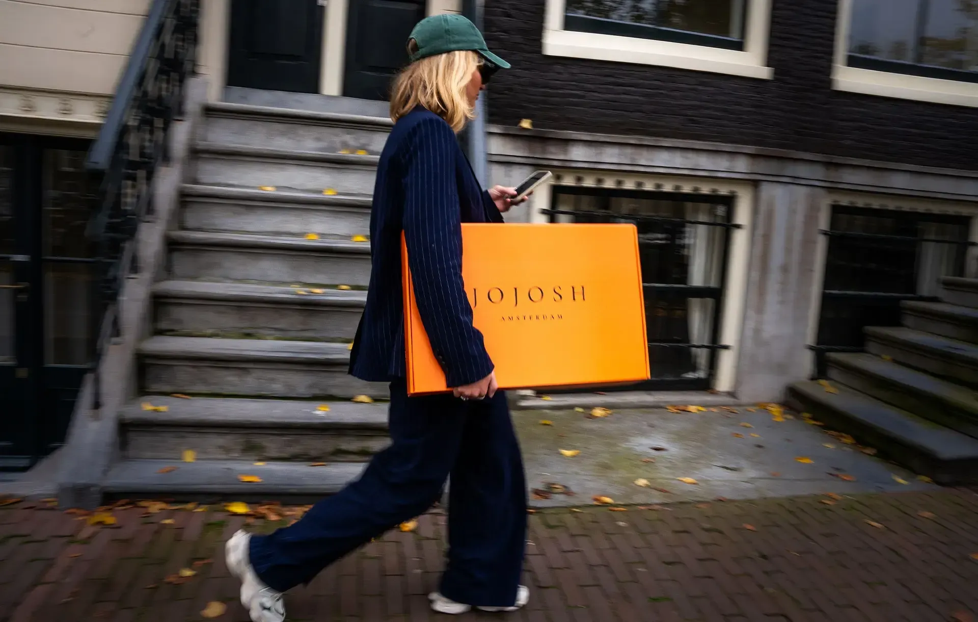 Een vrouw loopt de trap af met een oranje doos in haar handen.