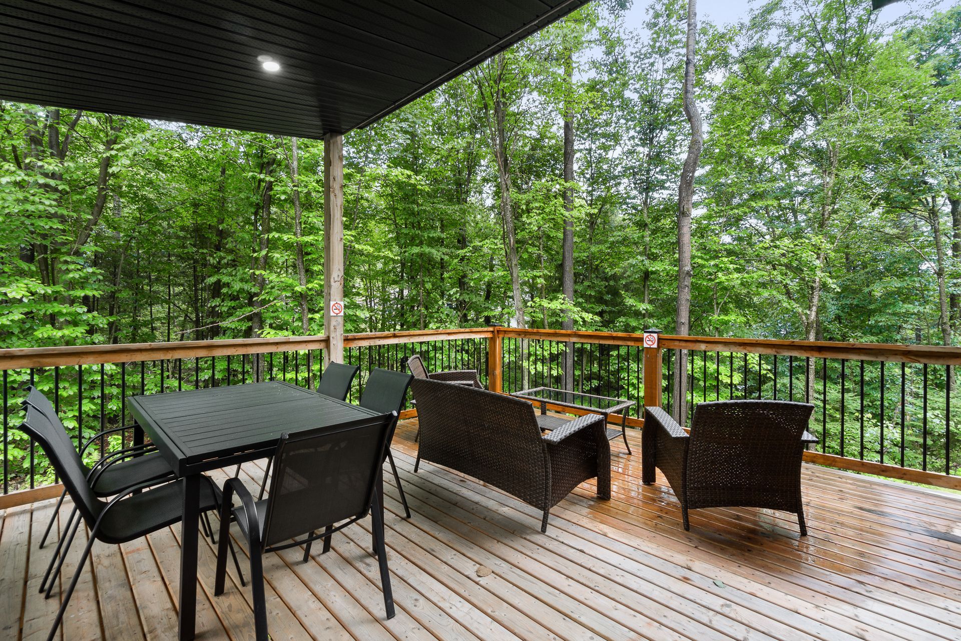 Terrasse en bois avec mobilier d'extérieur donnant sur une forêt verdoyante.