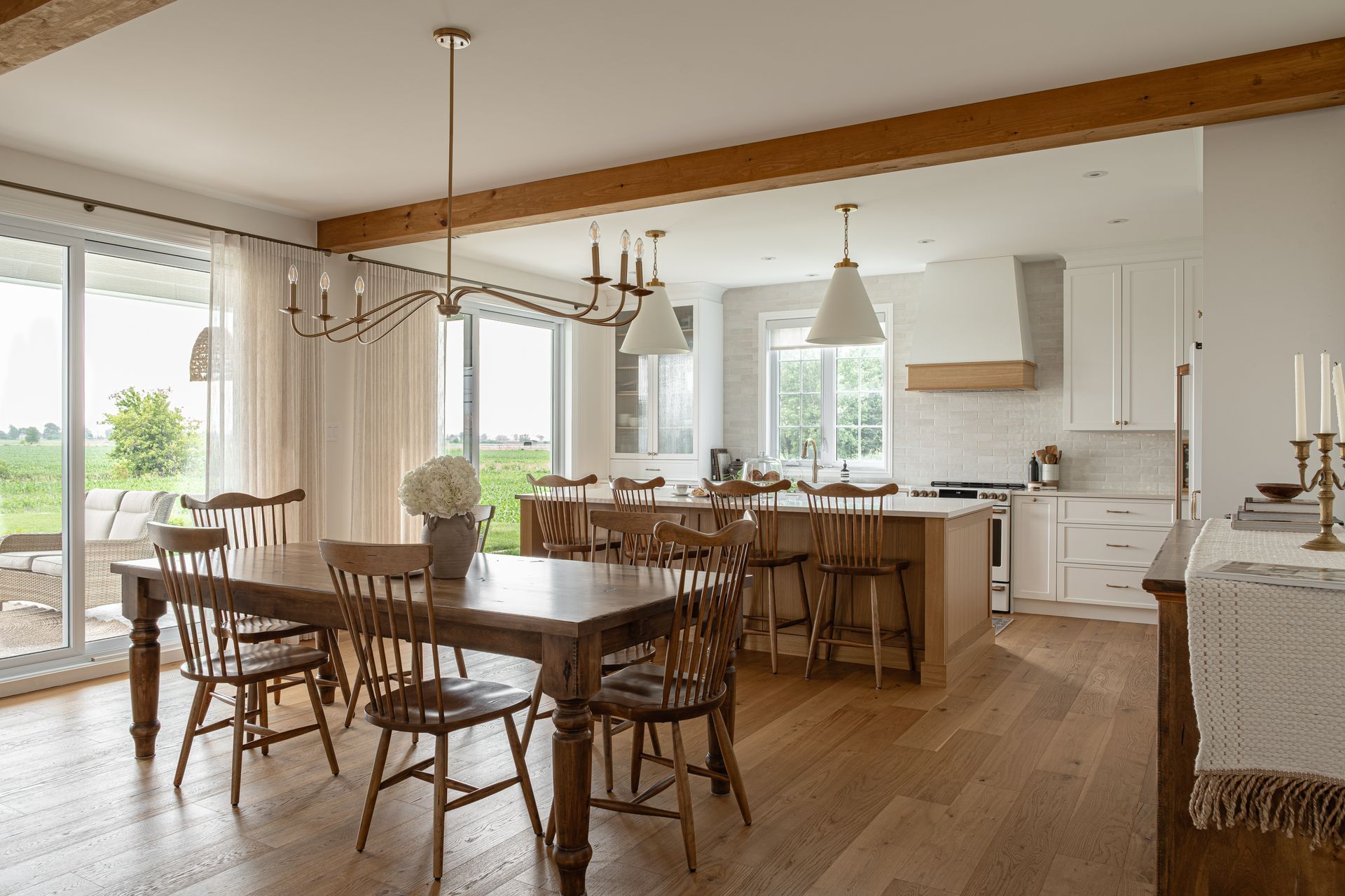 Salle à manger et cuisine avec une grande table et des chaises en bois, parquet en bois clair et vue.