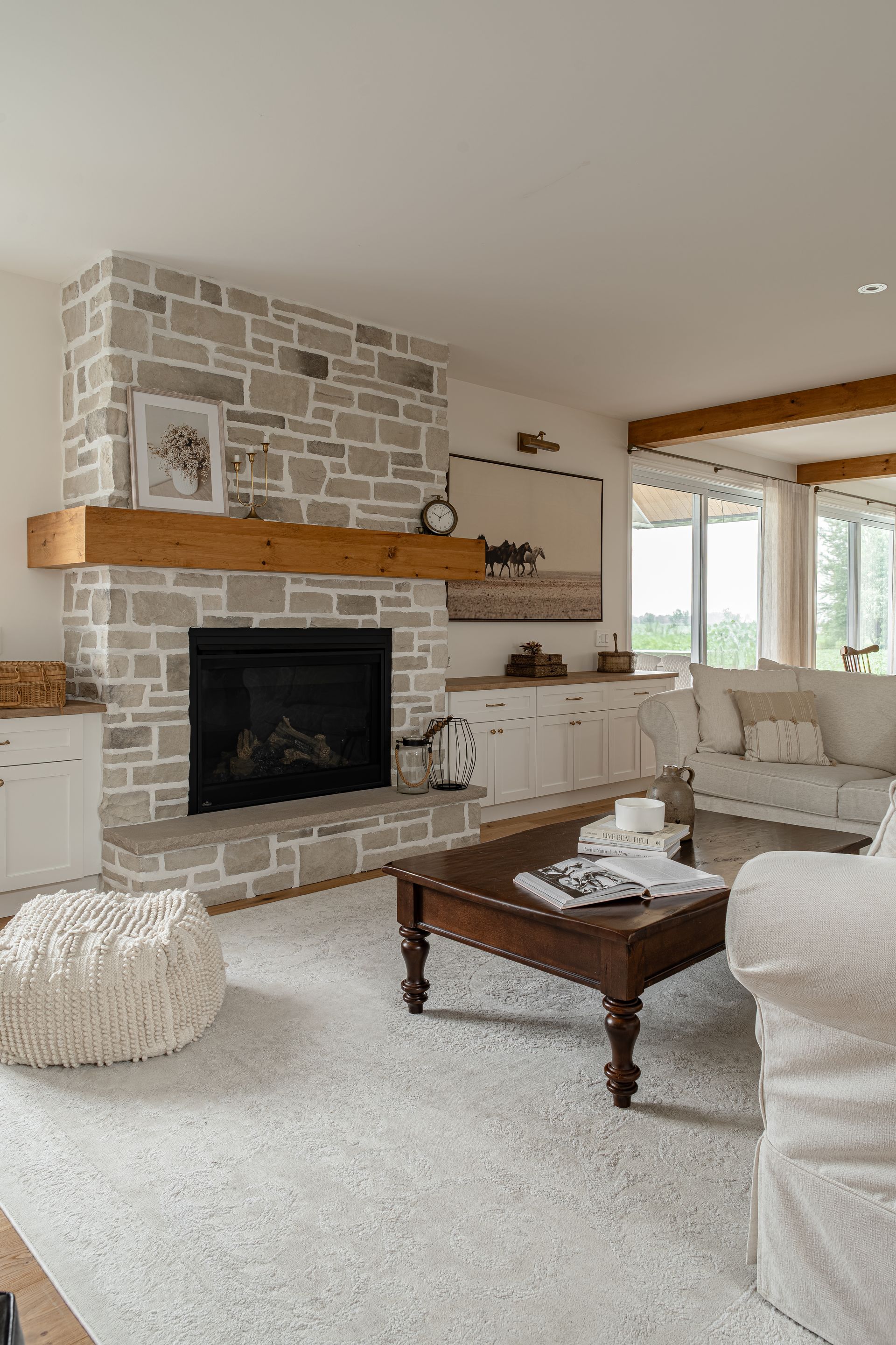 Salon avec cheminée en pierre, canapé blanc et table basse en bois.