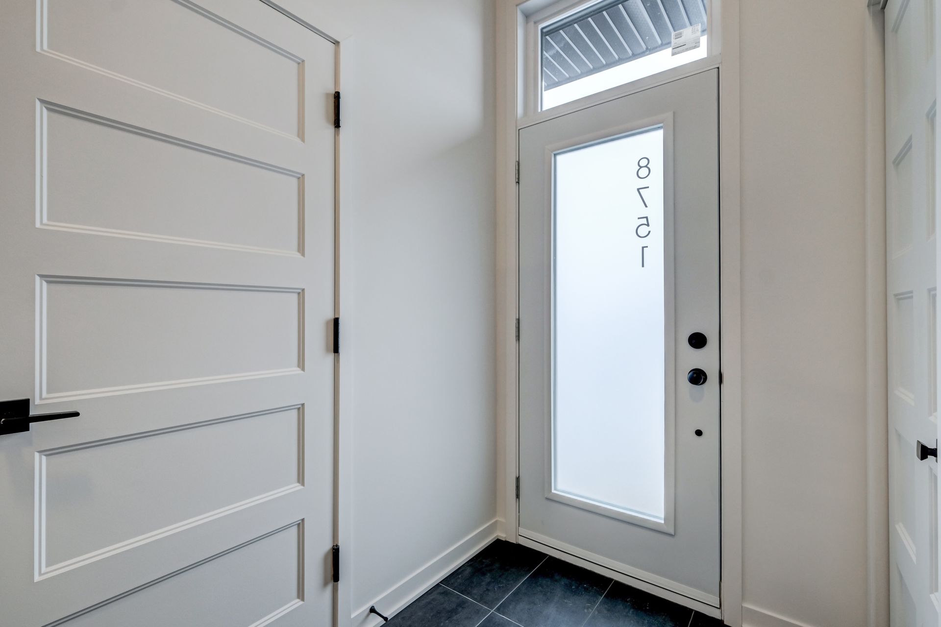 Portes intérieures blanches et porte d'entrée en verre dépoli.