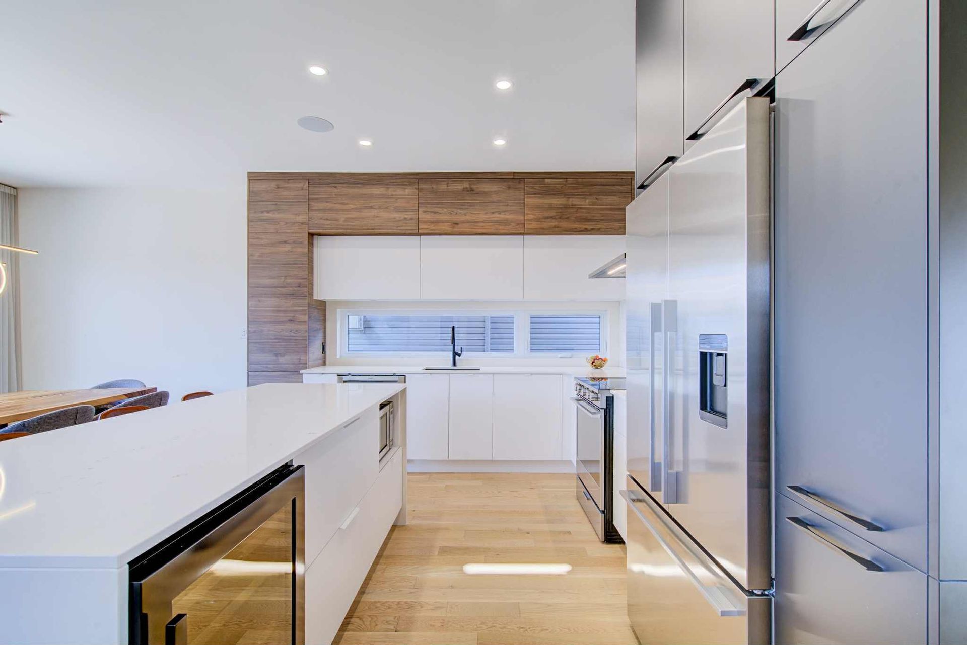 Cuisine moderne avec armoires blanches, appareils électroménagers en acier inoxydable et mur d'accent en bois.