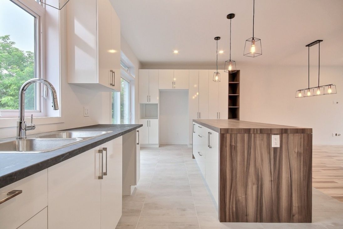 Cuisine blanche moderne avec îlot en bois et luminaires.