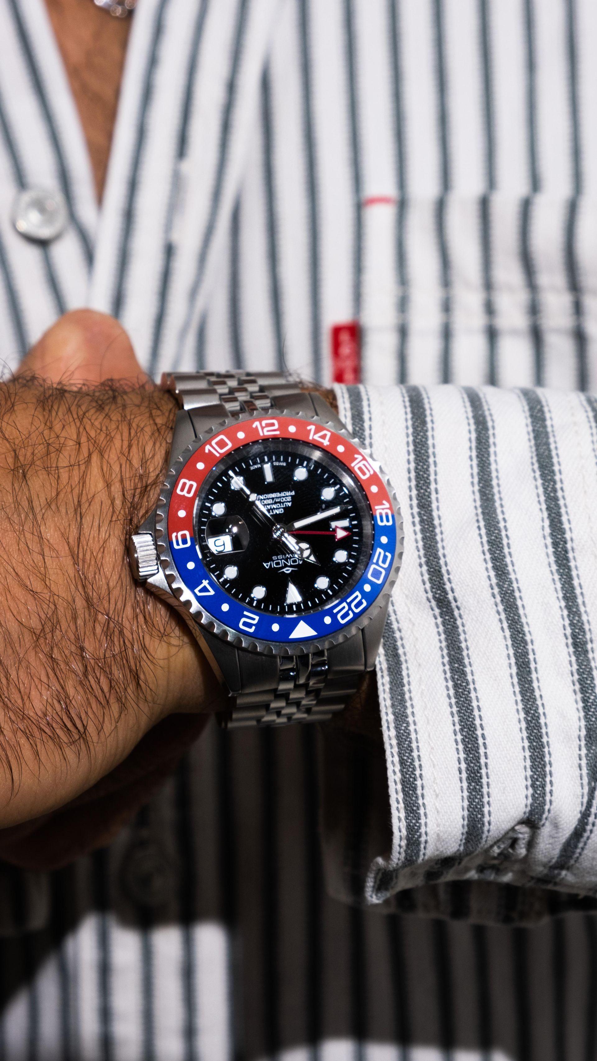 Un uomo che indossa una camicia a righe e un orologio al polso.