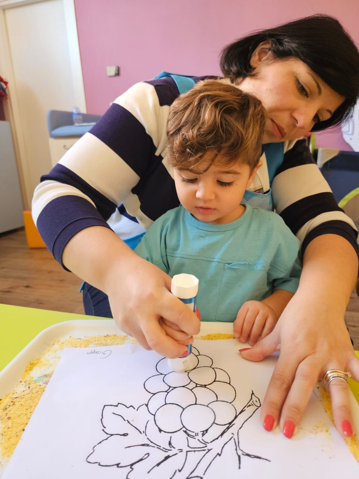 Una donna e un bambino stanno attaccando con la colla su un pezzo di carta