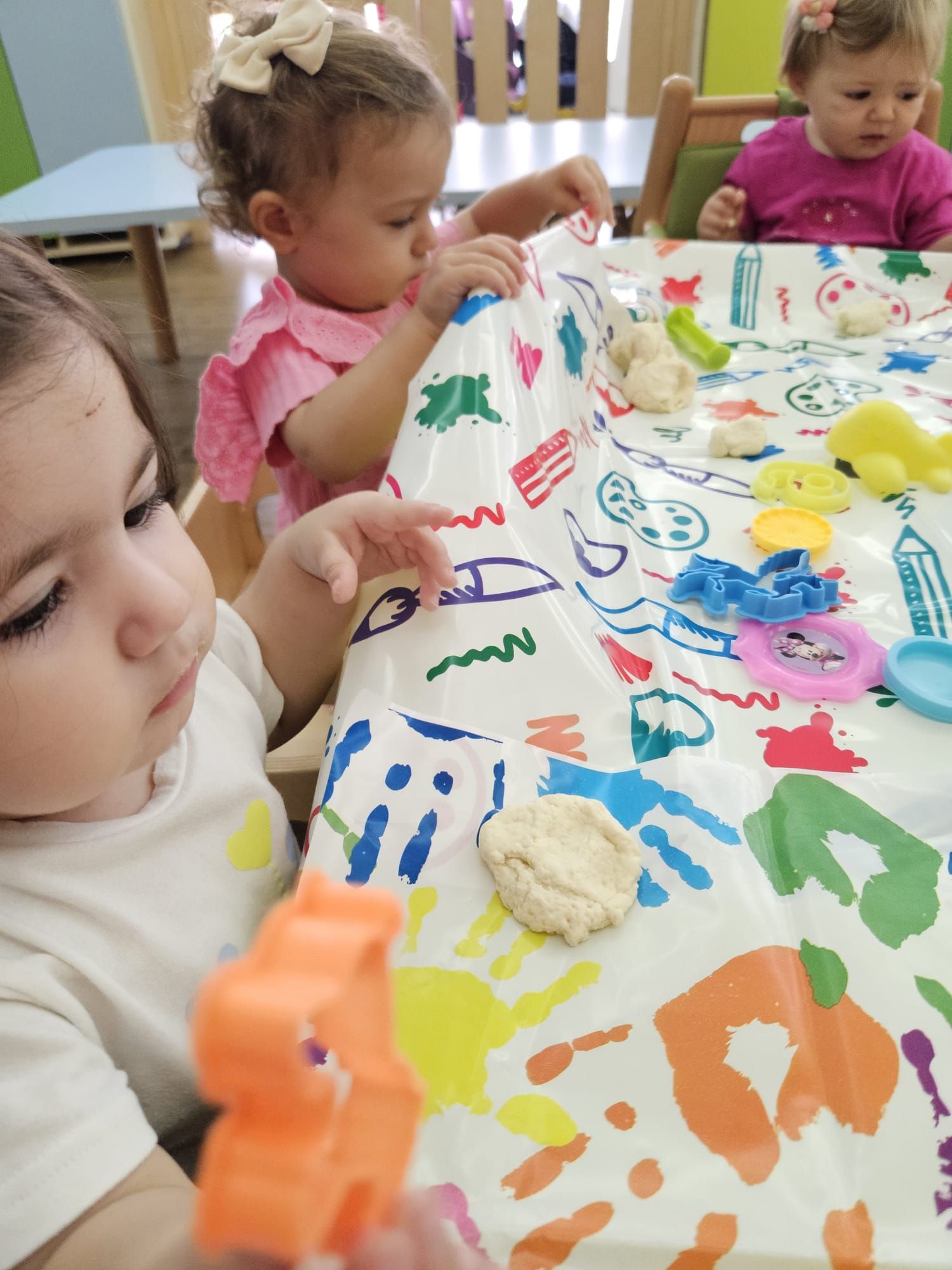 Tre bambine giocano con la pasta modellabile su un tavolo