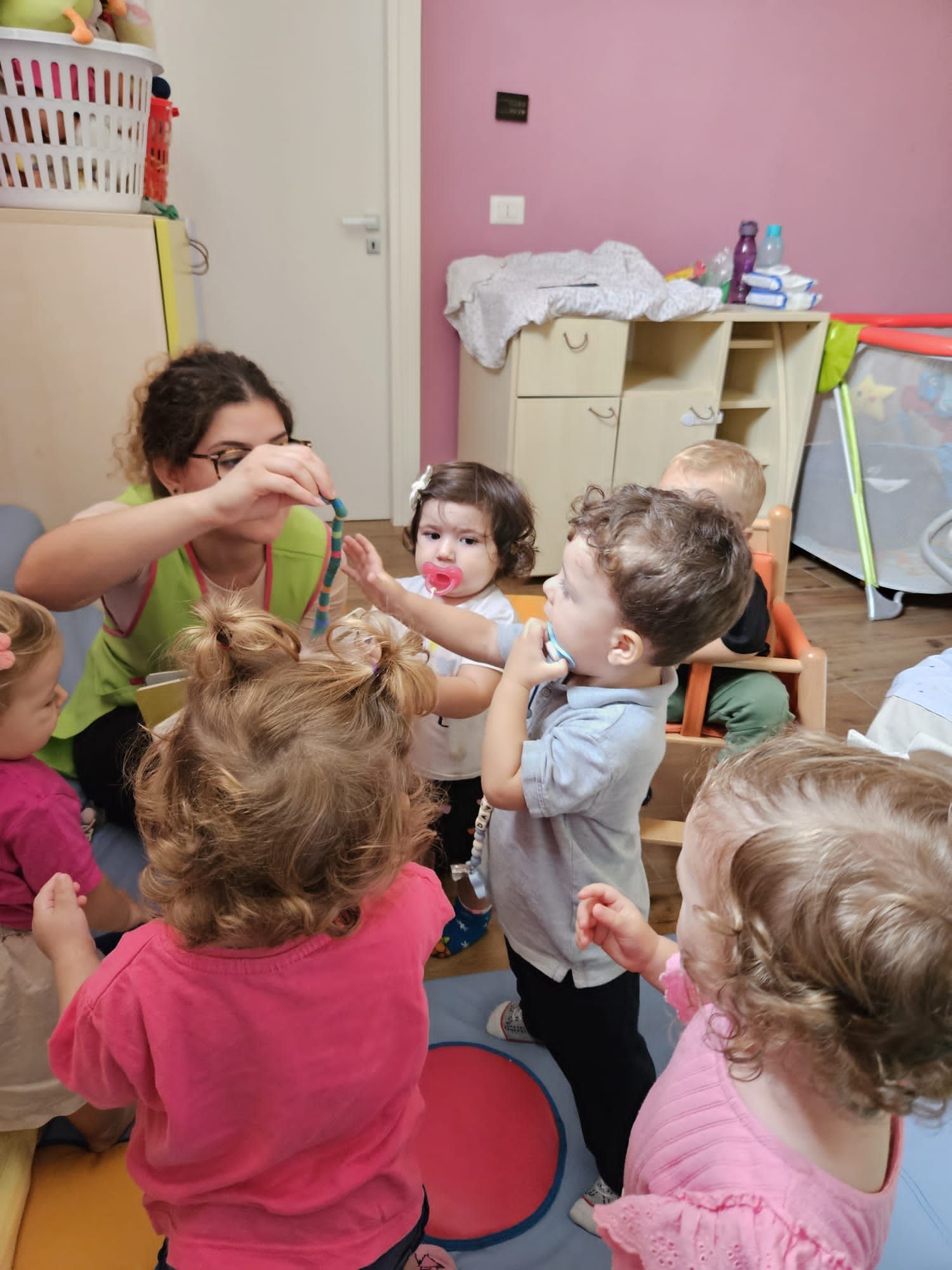 Una donna sta giocando con un gruppo di bambini in una stanza.