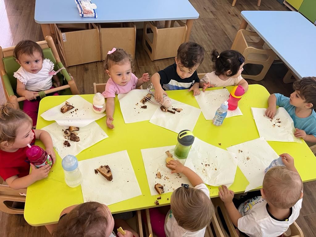 Un gruppo di bambini è seduto a un tavolo e mangia una torta.