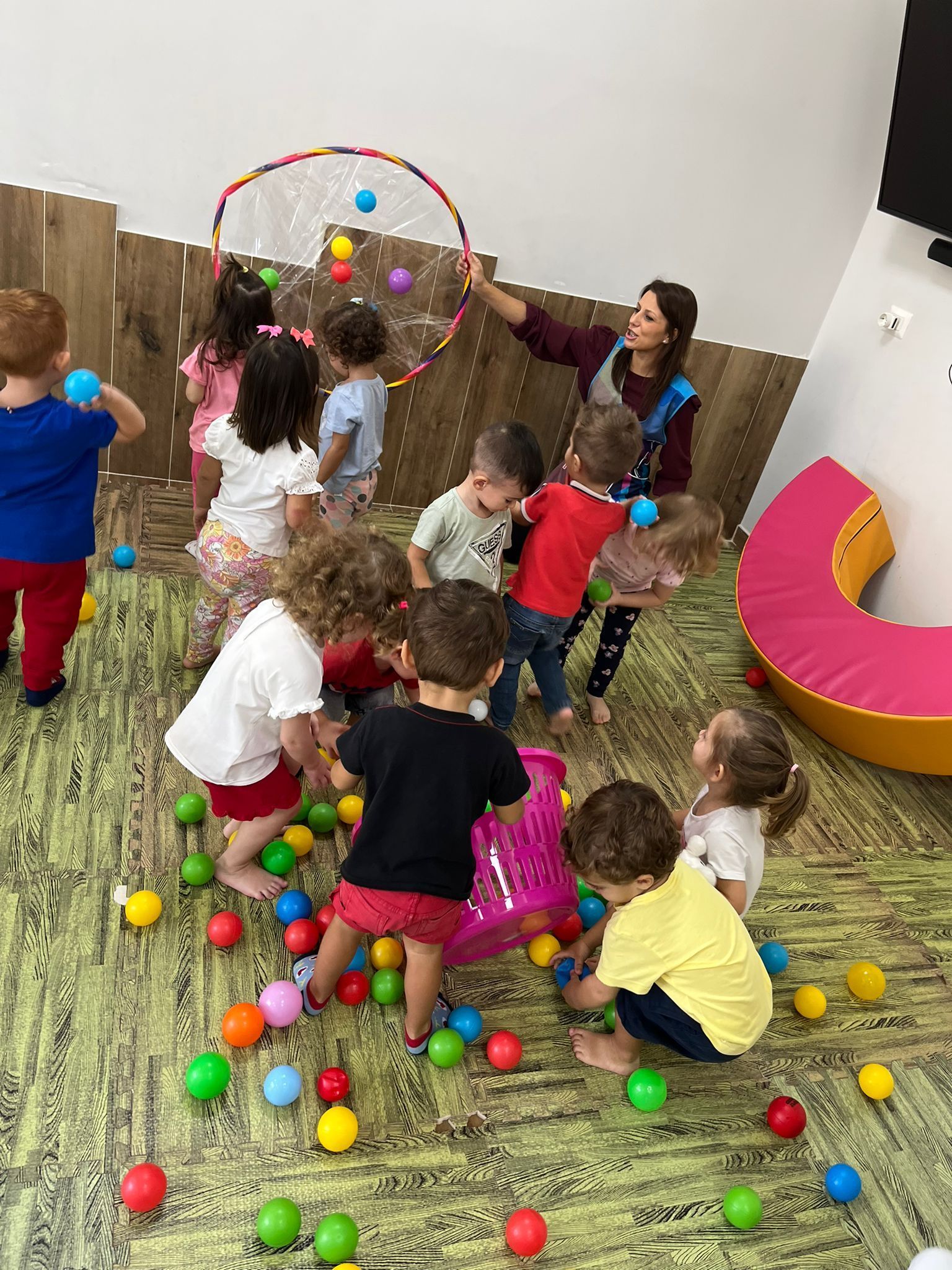 Un gruppo di bambini sta giocando con palline colorate sul pavimento.