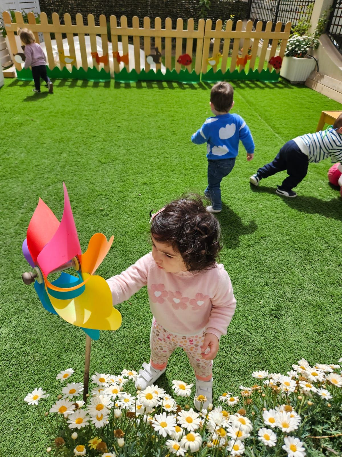 Una bambina tiene in mano un mulinello colorato in un campo di margherite