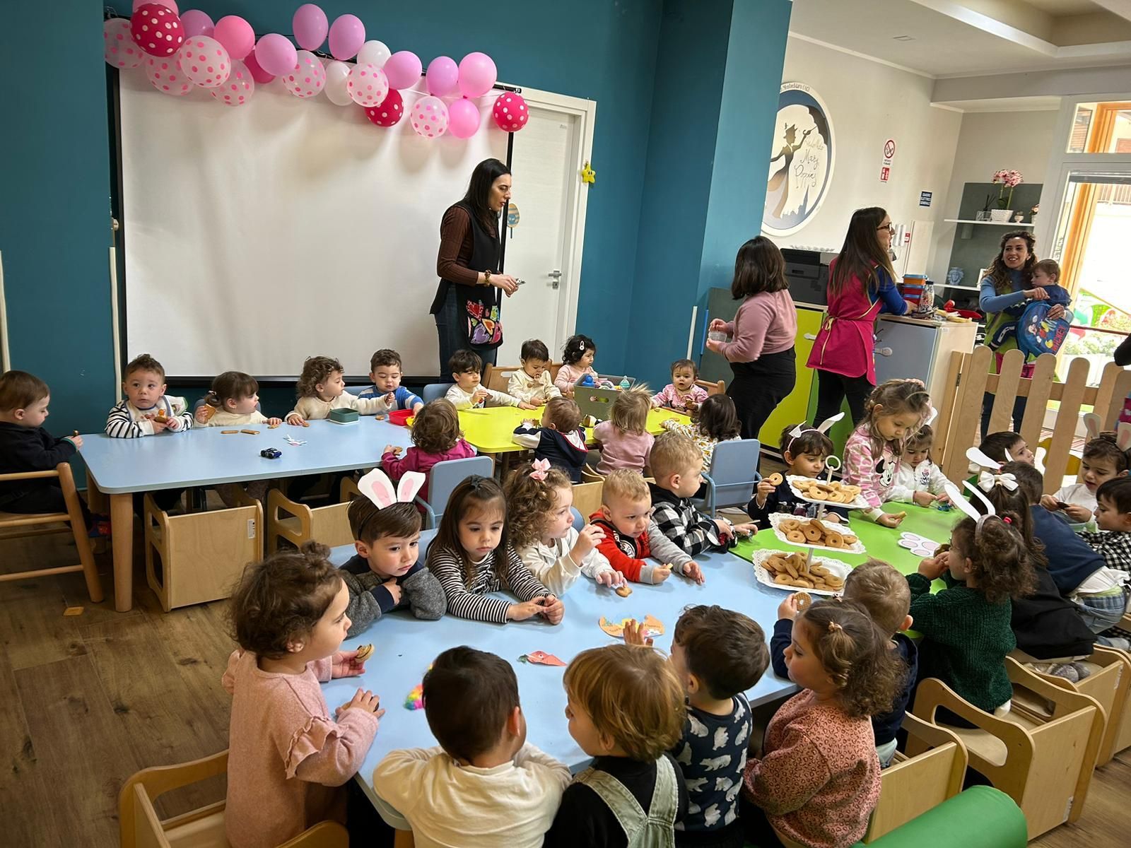 Un gruppo di bambini è seduto ai tavoli di un'aula e mangia cibo.
