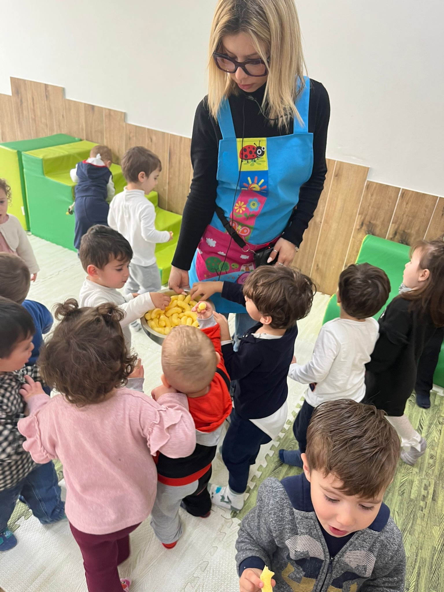 Una donna è in piedi davanti a un gruppo di bambini, mentre mangiano patatine