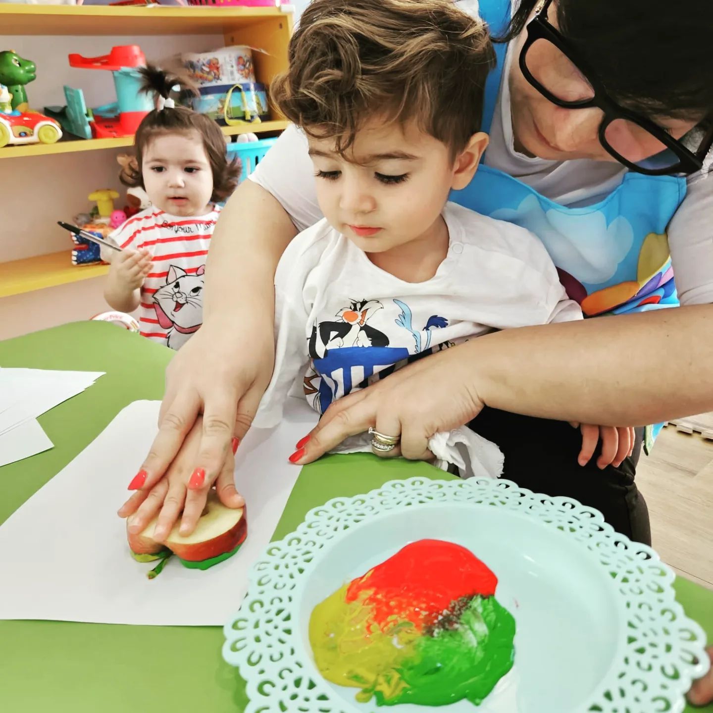 Una donna insegna a un ragazzino come dipingere una mela