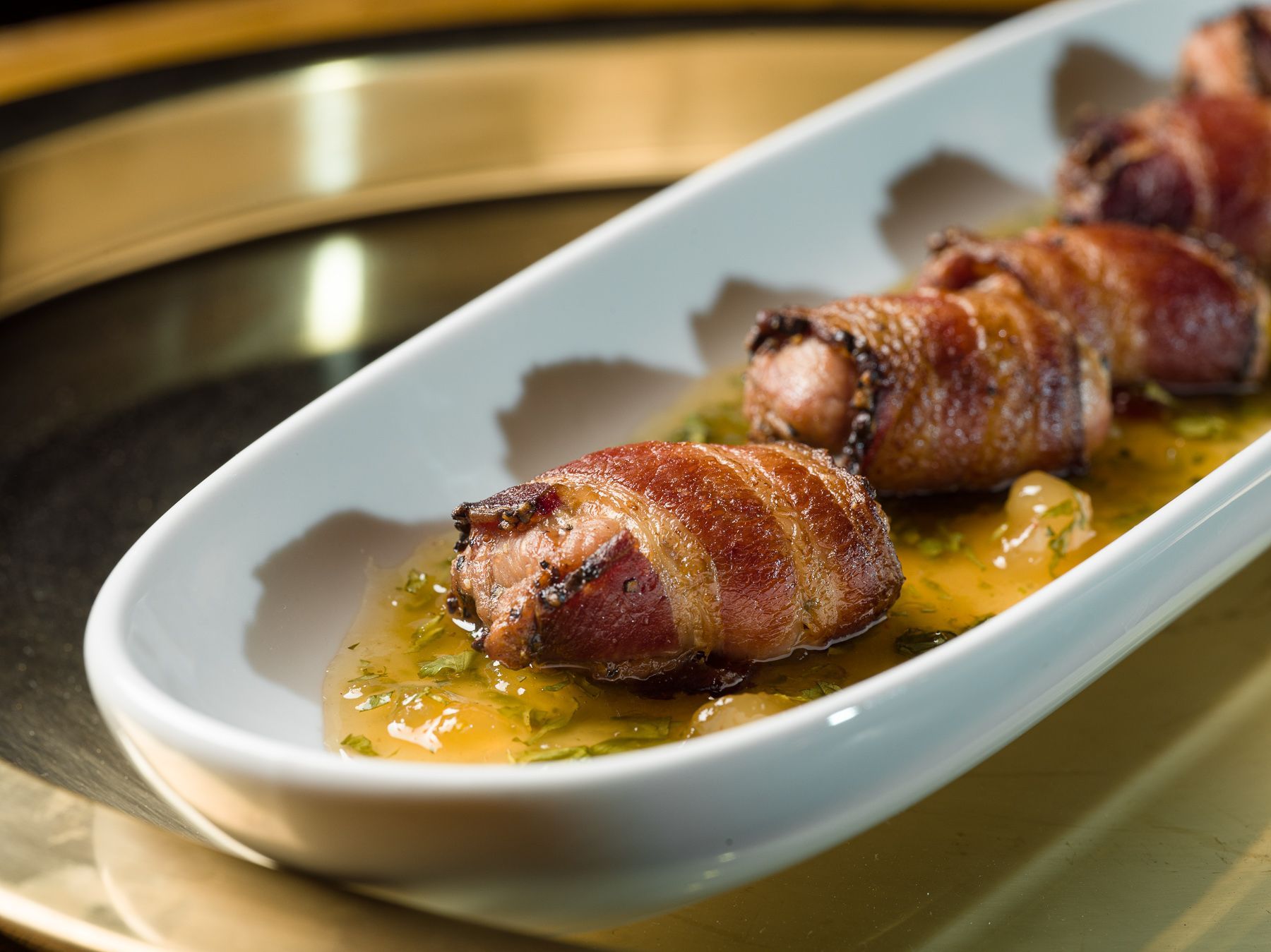 A white plate topped with bacon wrapped sausages