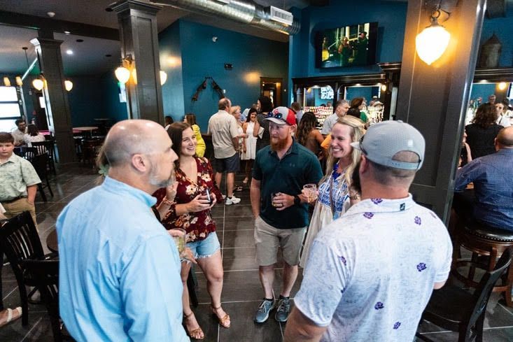 A group of people are standing in a restaurant talking to each other.