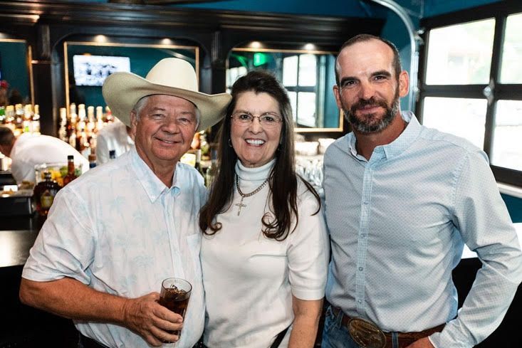 A man in a cowboy hat is standing next to a woman and a man.
