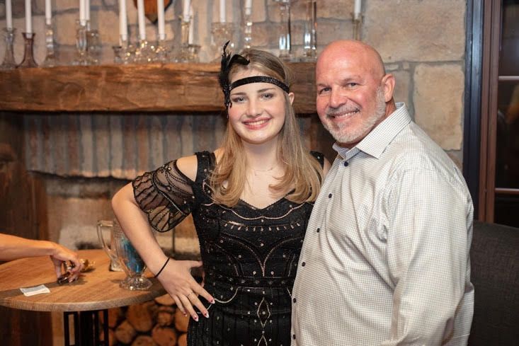 A man and a woman are posing for a picture in front of a fireplace.