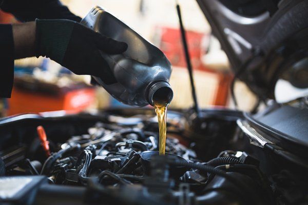 Professional mechanic pouring new oil — Valley City, ND — Quality Alignment & Brake Center