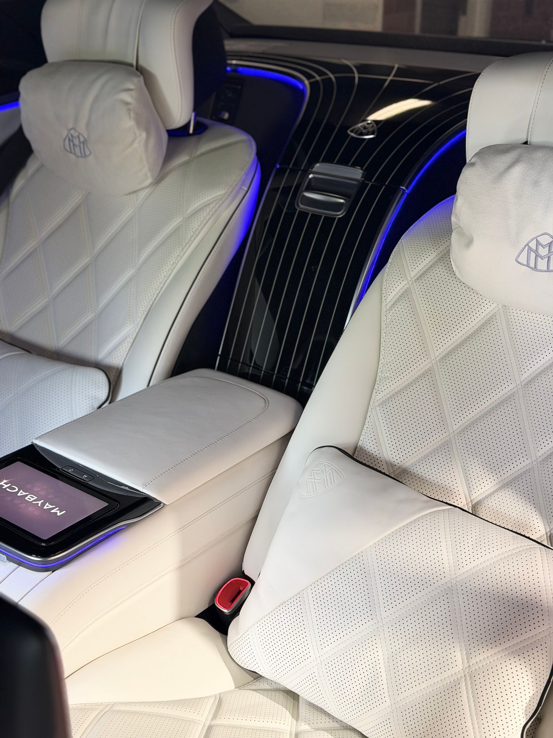 Luxury car interior with white quilted seats and blue ambient lighting between the front seats