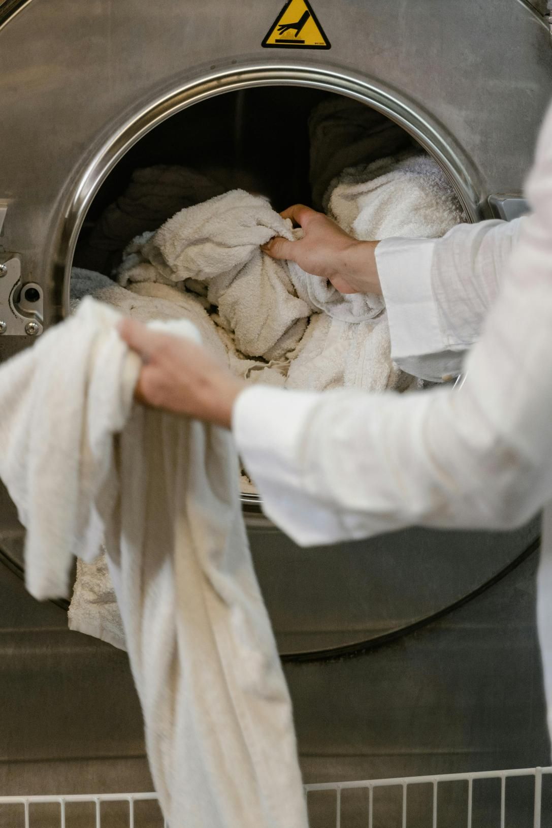A Person is Putting Clothes in a Washing Machine — Tuncurry Washerteria In Diamond Beach, NSW