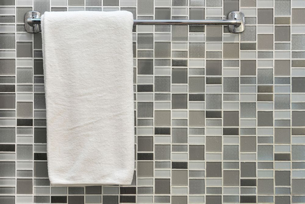 A white towel is hanging on a towel rack on a tiled wall. — Tuncurry Washerteria In Taree, NSW