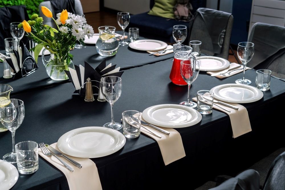 A Long Table With Plates, Glasses, Napkins and a Vase of Flowers on It — Tuncurry Washerteria In Tuncurry, NSW