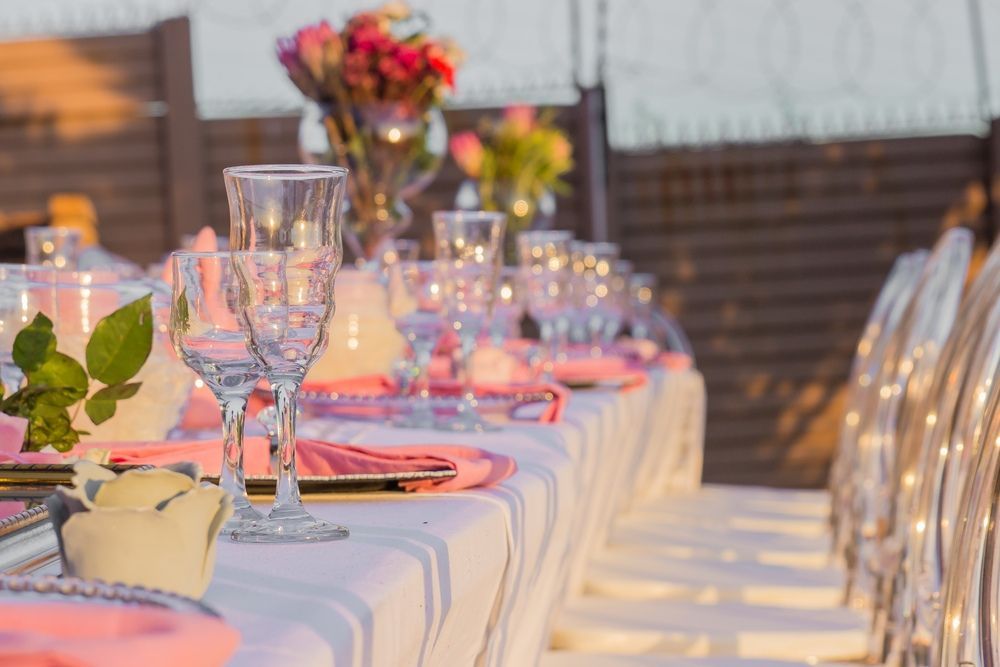 A Long Table With Plates , Glasses , and Flowers on It — Tuncurry Washerteria In Tuncurry, NSW