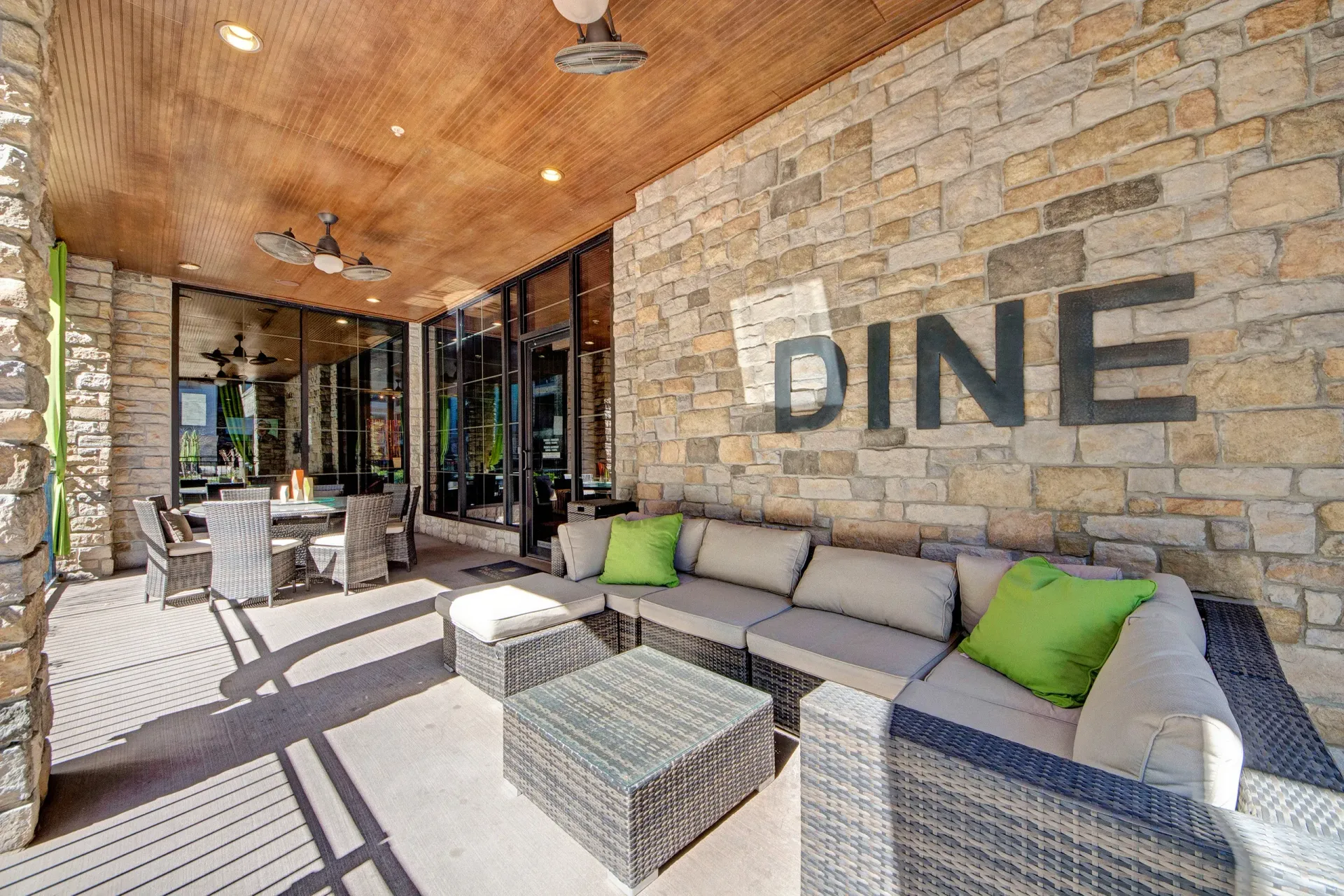 A patio with a couch , table , chairs and a sign that says dine.