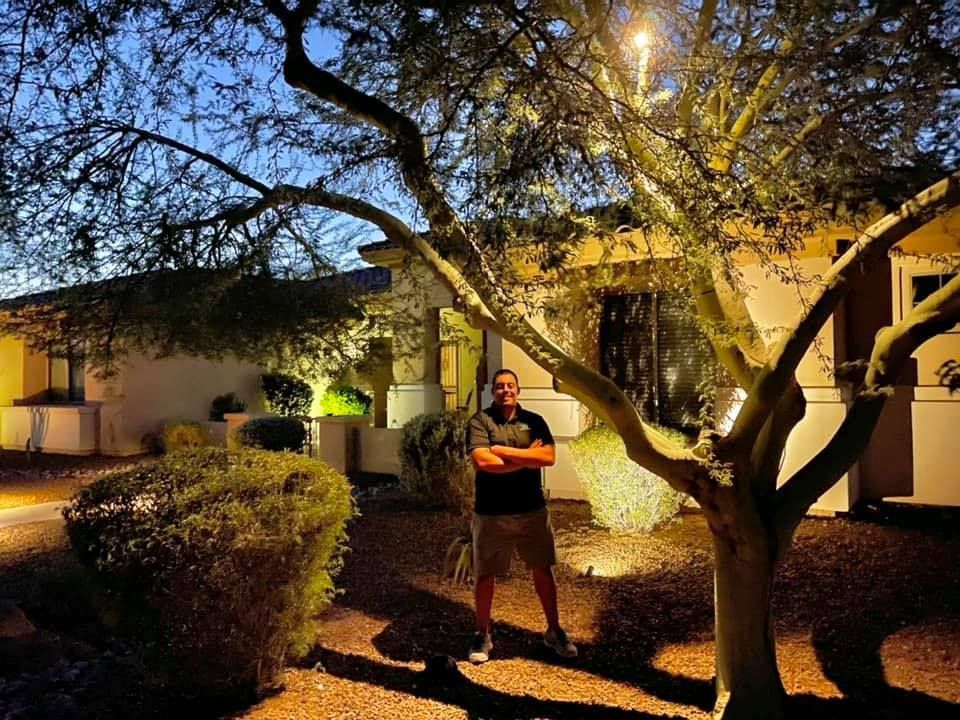 A man standing under a tree in front of a house